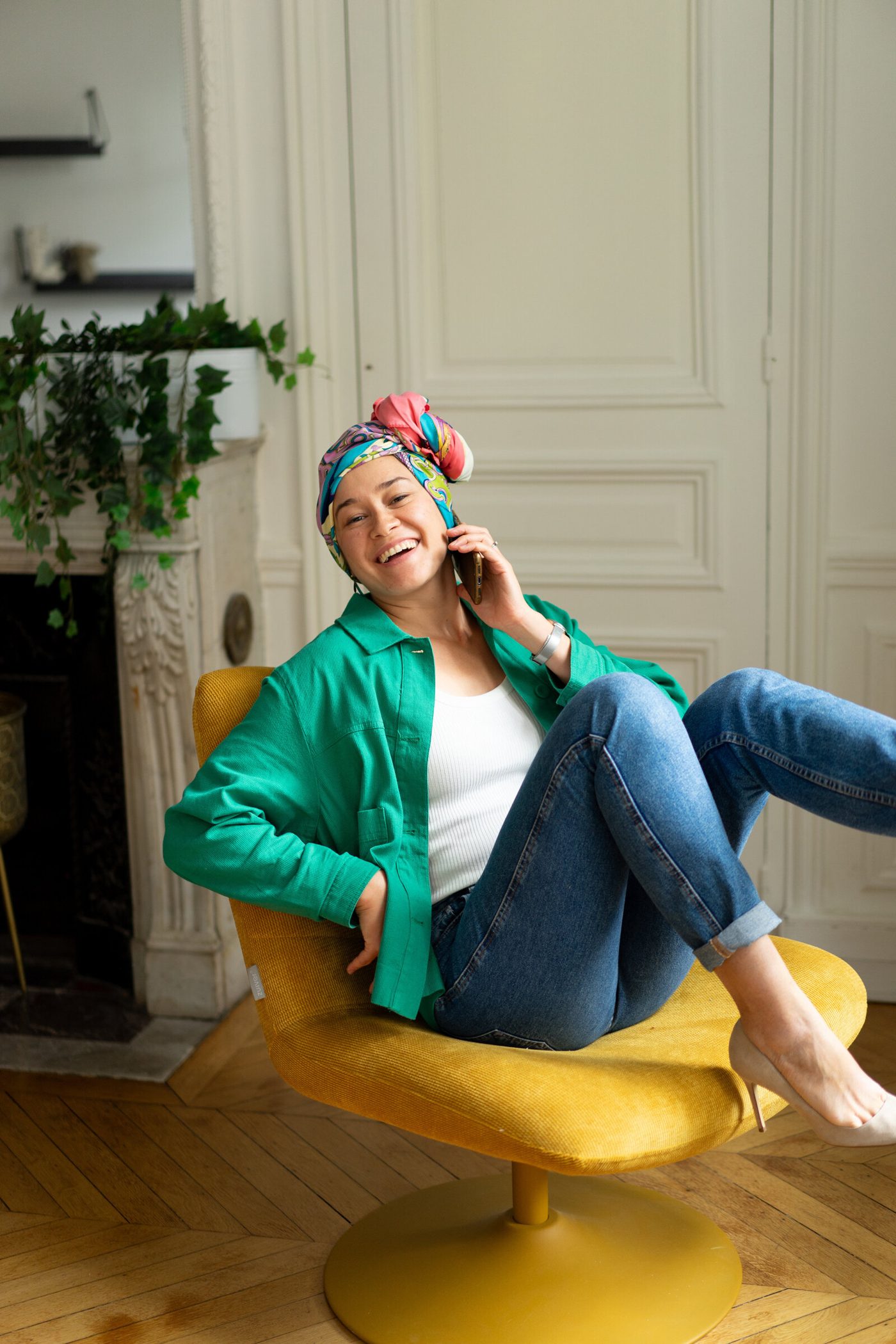 Aliya laughing on the phone in a yellow chair